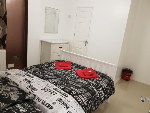 a bedroom with a bed with two red pillows on it at Taj Suite in Ipswich