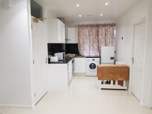 a white kitchen with a refrigerator and a dishwasher at Taj Suite in Ipswich