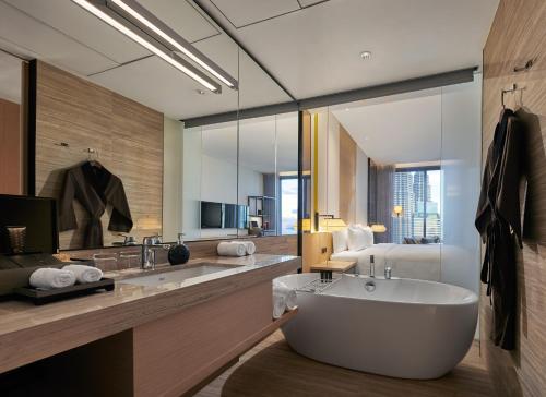 a bathroom with a large tub and a bedroom at EQ Kuala Lumpur in Kuala Lumpur