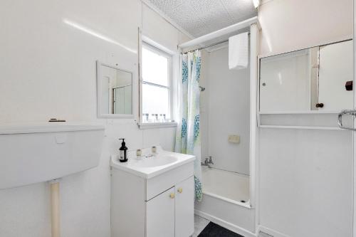 een witte badkamer met een wastafel en een douche bij 3 Bedroom In Onehunga w Parking - Wifi - Netflix in Auckland