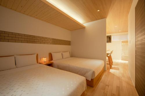 a bedroom with two beds and a table with a chair at HOTEL&CO in Fukuoka