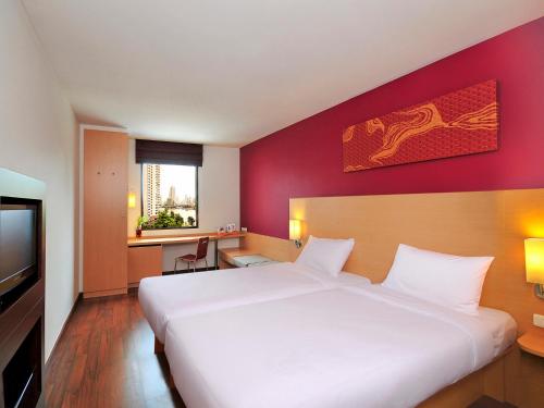a bedroom with a white bed and a red wall at Ibis Bangkok Riverside in Bangkok