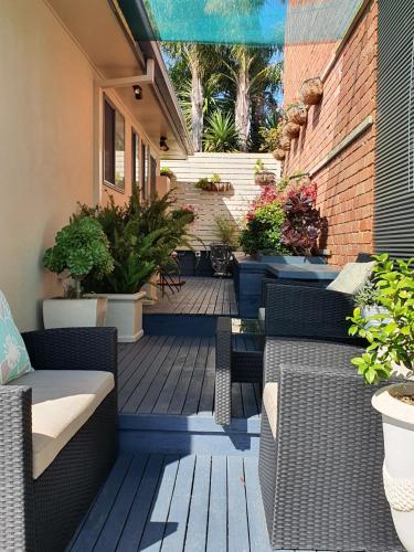 a patio with wicker chairs and potted plants at Abalone Guest Accommodation in Lakes Entrance