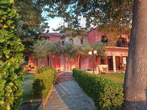 duży różowy dom z ścieżką przed nim w obiekcie Paparizou Apartments w mieście Kokino Nero