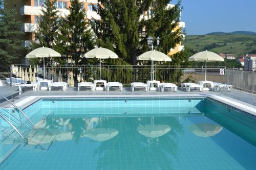 una piscina con sillas y sombrillas en Hotel Germisara en Geoagiu Băi