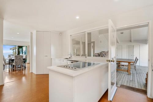 a kitchen with white cabinets and a dining room at Waitahanui Lakefront Escape - Waitahanui Home in Waitahanui