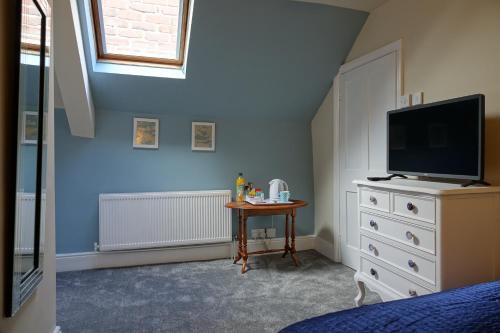 a bedroom with a tv on a dresser and a table at Kirkgate House in Knaresborough