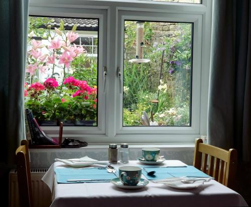 a table with two cups and two windows with flowers at Kirkgate House in Knaresborough