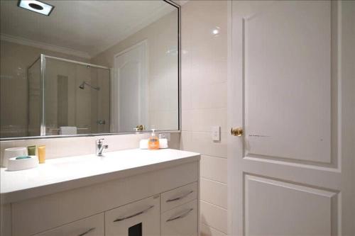 a bathroom with a sink and a mirror and a door at Swan River Apartment in Perth