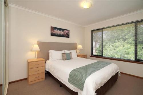 a bedroom with a bed and a large window at Swan River Apartment in Perth