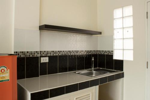 a kitchen with a sink and black and white tiles at Nattidaplace Hotel Chiangmai in Chiang Mai