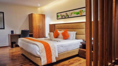 a bedroom with a bed with orange and white pillows at Kyriad Hotel Gulbarga by OTHPL in Gulbarga