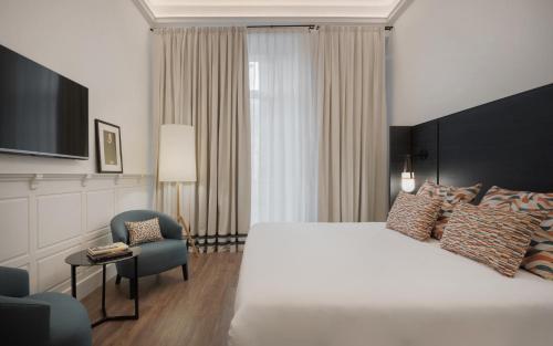 マラガにあるTOC Hostel Malagaの大きなベッドと椅子が備わるホテルルームです。