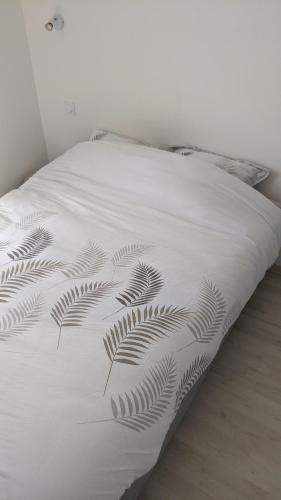 a white bed with a plant printed on it at Maison Jean-Moulin, jardin, spacieuse, 24h Mans, zoo, Prytanée, 3 chbres, 6 pers in La Flèche