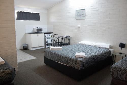 a bedroom with a bed with two towels on it at The Plains Motor Inn in Gunnedah