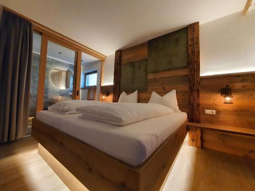 een slaapkamer met een groot bed en een groot raam bij HIESERHOF - Superior Alpine Apartments in Heiligenblut