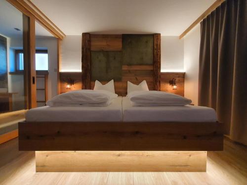 a bedroom with a large bed with a wooden headboard at HIESERHOF - Superior Alpine Apartments in Heiligenblut