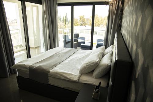 a bedroom with a bed and a large window at Jimmy's Suites in Larnaka