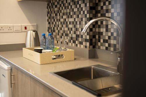 a kitchen counter with a sink and a box of water bottles at Jimmy's Suites in Larnaka