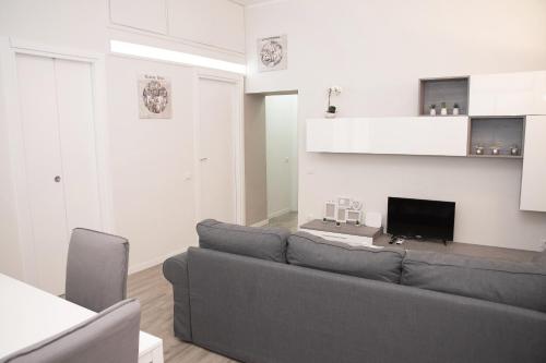 uma sala de estar com um sofá cinzento e uma televisão em La Dimora del Cardinale em Roma
