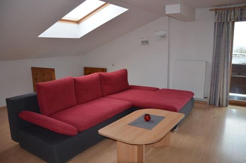 a red couch in a living room with a table at Bauernhof Grafenhof in Ebbs