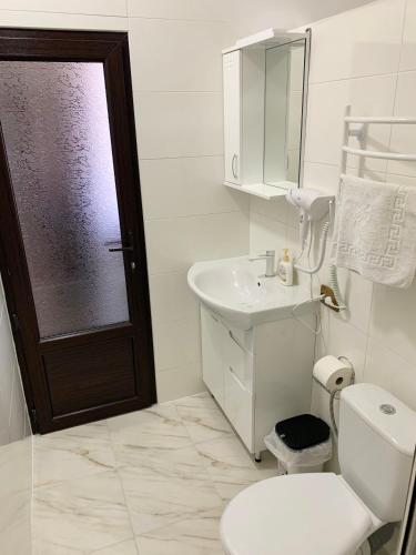 a white bathroom with a toilet and a sink at готель Вікторія in Volovets