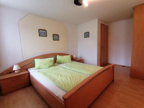 Un dormitorio con una gran cama de madera con almohadas verdes en Bauernhof Grafenhof, en Ebbs