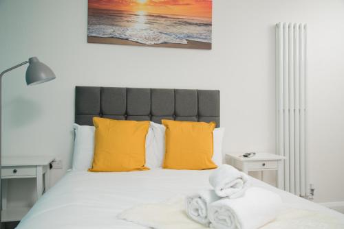 a bedroom with a large bed with yellow pillows at TLK Apartments & Hotel - Beckenham High Street in Beckenham
