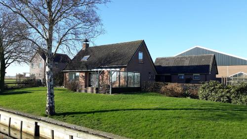 a black house with a tree in the yard at Vakantiehuisje 't Wiede in Blokzijl