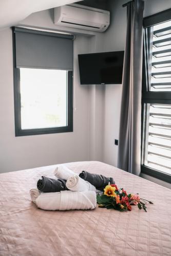 a bed with towels and a bouquet of flowers on it at cobalt aqua in Iraklitsa