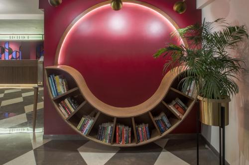 a large red wall with a book shelf with books at T24 Retro in Mumbai
