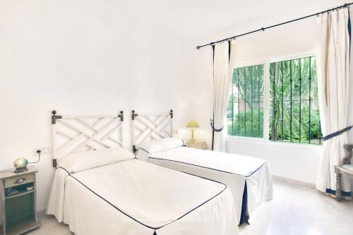 2 letti in una camera bianca con finestra di Apartamento entre Marbella y Estepona a Estepona