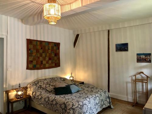 a bedroom with a bed and a chandelier at Gîte Vanakam 3 étoiles- jolie maison béarnaise 9 personnes avec piscine in Sault-de-Navailles