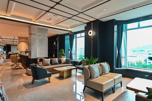 a living room with couches and chairs and windows at Wyndham Qingdao l Free Fixed-Time Shuttle Service Between Hotel and Airport & North Railway Station l Outdoor Children's Amusement Park l 1-Hour Play Snooker or Table Tennis in Qingdao