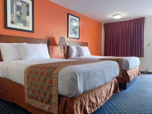 duas camas num quarto de hotel com paredes cor de laranja em Royal Inn Richmond Hill- Savannah I-95 em Richmond Hill