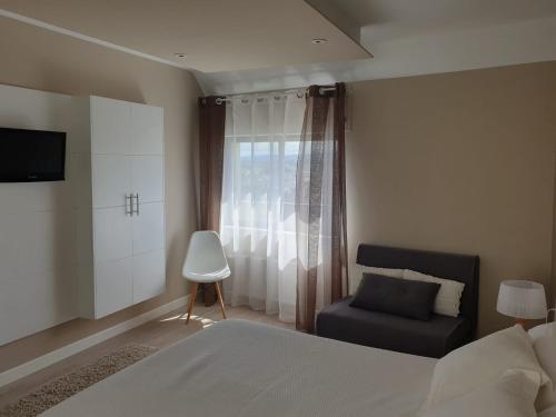 1 dormitorio con 1 cama, 1 silla y 1 ventana en Apartamento centro Ribadeo, en Ribadeo