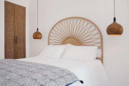 a bedroom with a white bed and two pendant lights at Koukoumi Vegan Boutique Hotel in Ano Mera