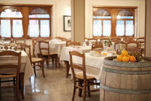 a dining room with tables and chairs and fruit on a barrel at Albergo Trattoria Speranza in Foza