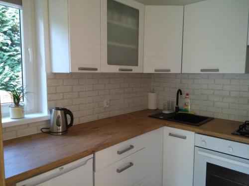 a kitchen with white cabinets and a wooden counter top at Dom gościnny Ania, Apartament nr 7 in Wisełka