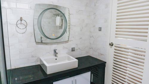 a white bathroom with a sink and a mirror at House of Belasun in Pelabuhan Ratu
