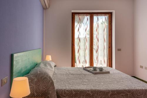 Schlafzimmer mit einem Bett und einem Fenster in der Unterkunft Residence Le Pavoncelle in Santa Teresa Gallura