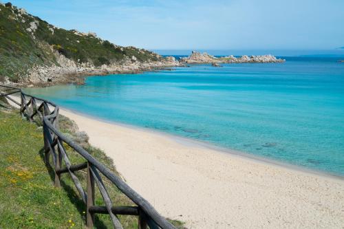 a beach with a wooden fence next to the ocean at Residence Le Pavoncelle in Santa Teresa Gallura