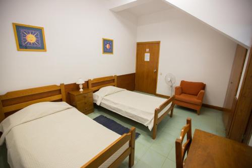a hospital room with two beds and a chair at HI Faro – Pousada de Juventude in Faro