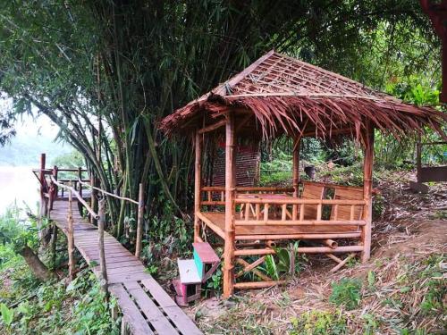 a hut with a straw roof and a wooden walkway at Betik Garden Home in Machang