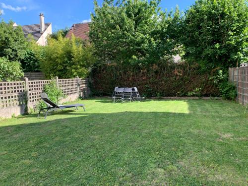 a garden with a table and a bench in the grass at Appart'Village Jouy Les Metz in Jouy-en-Josas