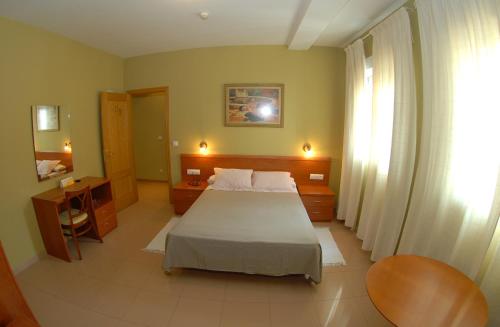 a bedroom with a bed and a desk and a window at Hotel Dora in Plasencia