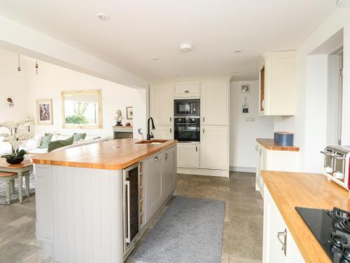 a kitchen with white cabinets and a wooden counter top at The Coach House in Sleaford