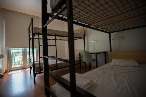a bedroom with two bunk beds and a table with a chair at HI Melgaco - Pousada de Juventude in Melgaço
