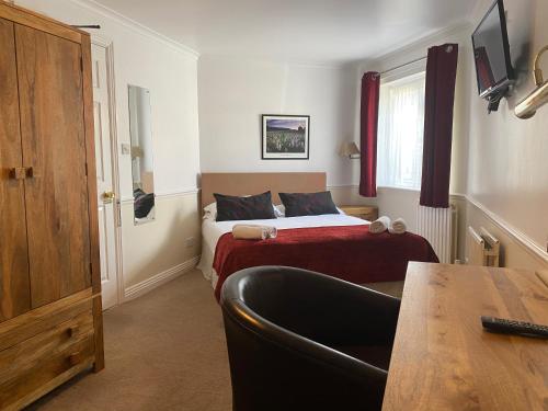 ein kleines Schlafzimmer mit einem Bett und einem Tisch darin in der Unterkunft Byways Serviced Apartments in Salisbury