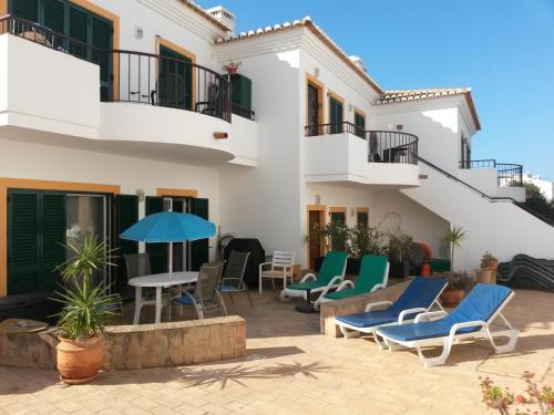 une terrasse en face d'un bâtiment avec des chaises et des tables dans l'établissement Casa Carmela, à Burgau